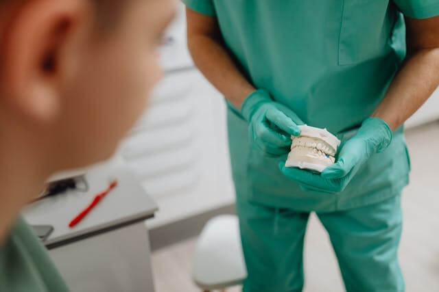 A Person Wearing Green Gloves Holding a Dental Mold A Person Wearing Green Gloves Holding a Dental Mold