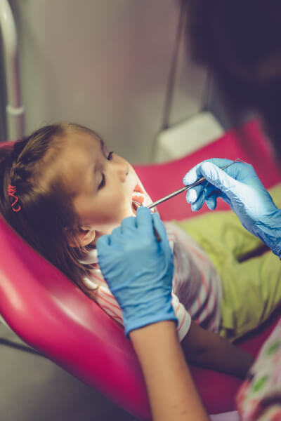 Dentist examining little girl in her office